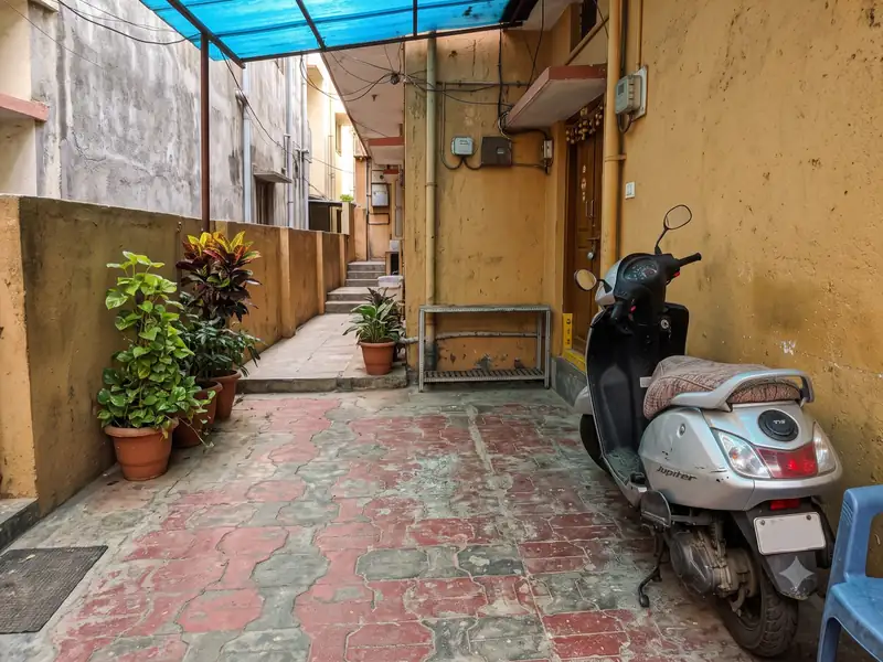 Scooter parked under a blue shade next to a residential doorway